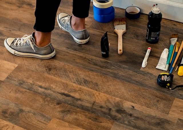 person in black pants standing on brown wooden floor