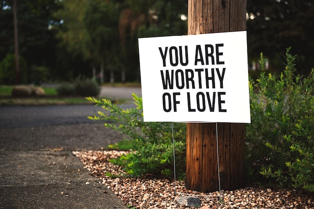 you are worthy of love sign beside tree and road