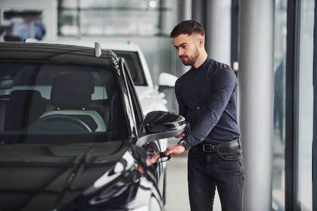 young man in formal clothes is near car